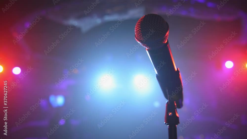Sweeping close up of stage microphone under colorful spotlights Stock