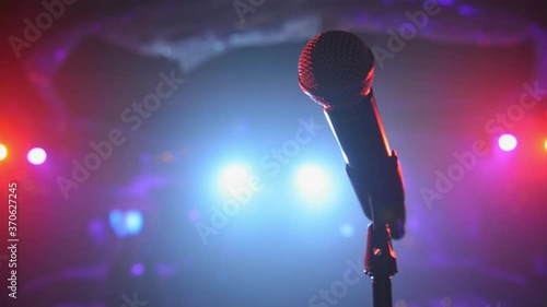Sweeping close up of stage microphone under colorful spotlights 