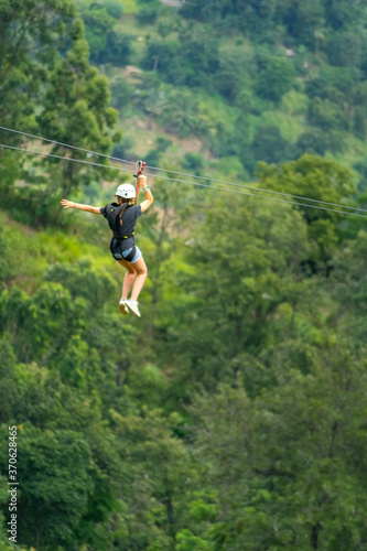 Young woman going on a zipline in the jungle. tree climbing in Sri Lanka. adventure , challenge and sport concept photo