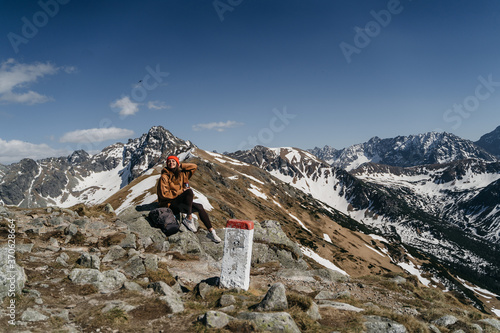  young woman in the mountains with a backpack drinks water. Active rest in one with nature