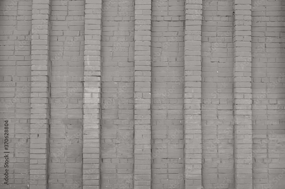 Facade of an old brick building. Gray brick wall with vertical columns. Background or texture of gray concrete wall. Contemporary urban architecture. Facade of an old brick building. Gray brick wall with vertical columns. Background or texture of gray concrete wall. Contemporary urban architecture.