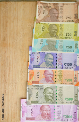 Closeup of brand new colorful Indian currency bank notes of 10, 20 yellow, 50, purple 100, 200, 500 and pink 2000 rupees bundle issued and in circulation after demonetisation against brown background photo