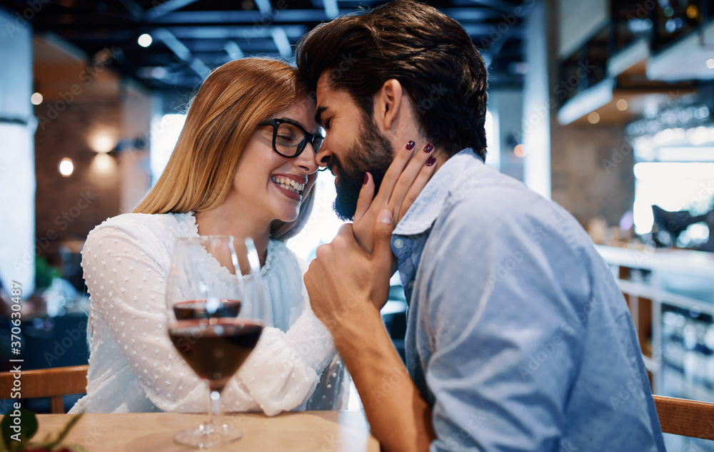Dating in the cafe. Beautiful couple drinking wine and enjoying in conversation. Dating, love, relationships