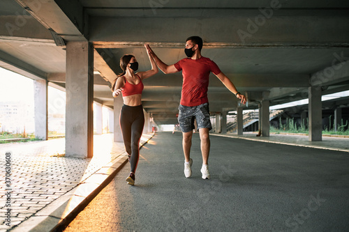 Couple running in an urban environment wearing protective masks