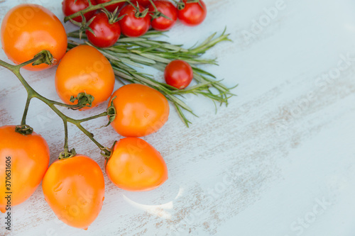 Various colorful tomatoes and rosemary herb on light blue background