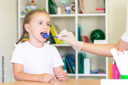 Speech therapy massage of the girl's tongue. a speech therapist makes a tongue massage to a child with a staging probe. photo