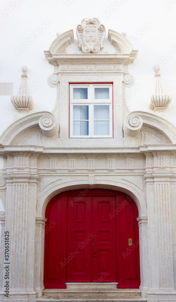 Red door on historic white building with window on top in Lisbon, Portugal