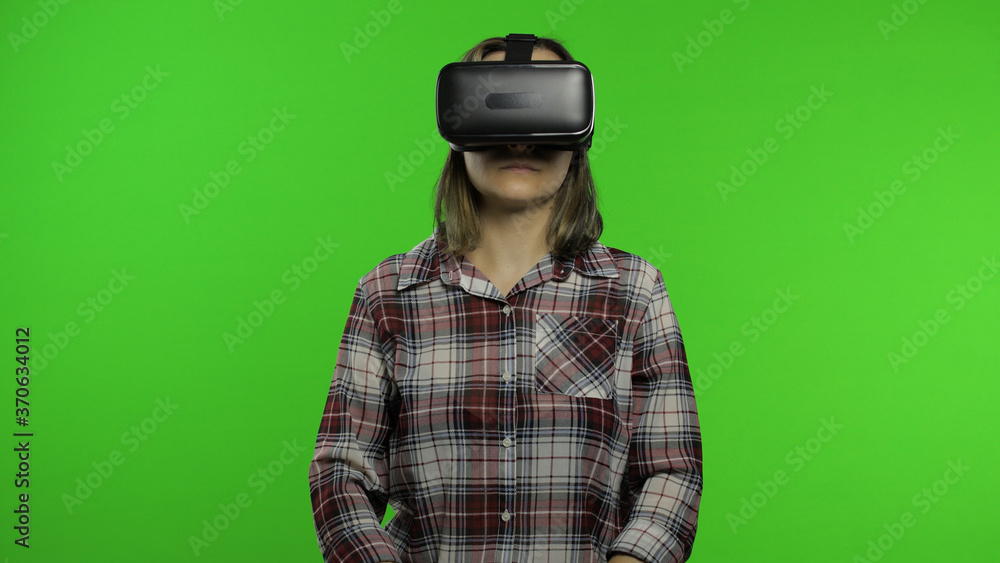 Young woman using VR headset helmet to play game. Watching virtual reality 3d 360 video. Chroma key