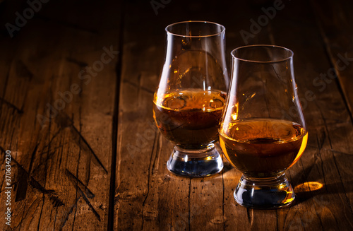 Scotch Whiskey without ice in glasses, rustic wood background, copy space