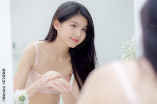 Beautiful sexy young asian woman looking mirror applying cream on hand and message  beauty girl applying body lotion skin care for health and soft hydration  treatment and cosmetic with moisturizer.