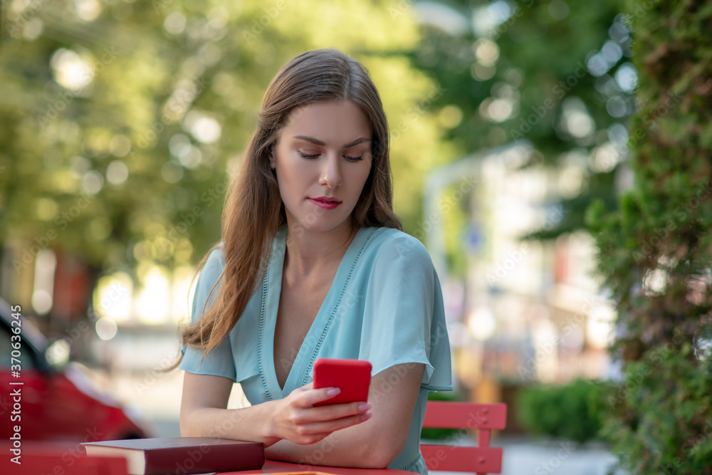 Upset female sitting in cafe, checking phone, biting lips Upset female sitting in cafe, checking phone, biting lips