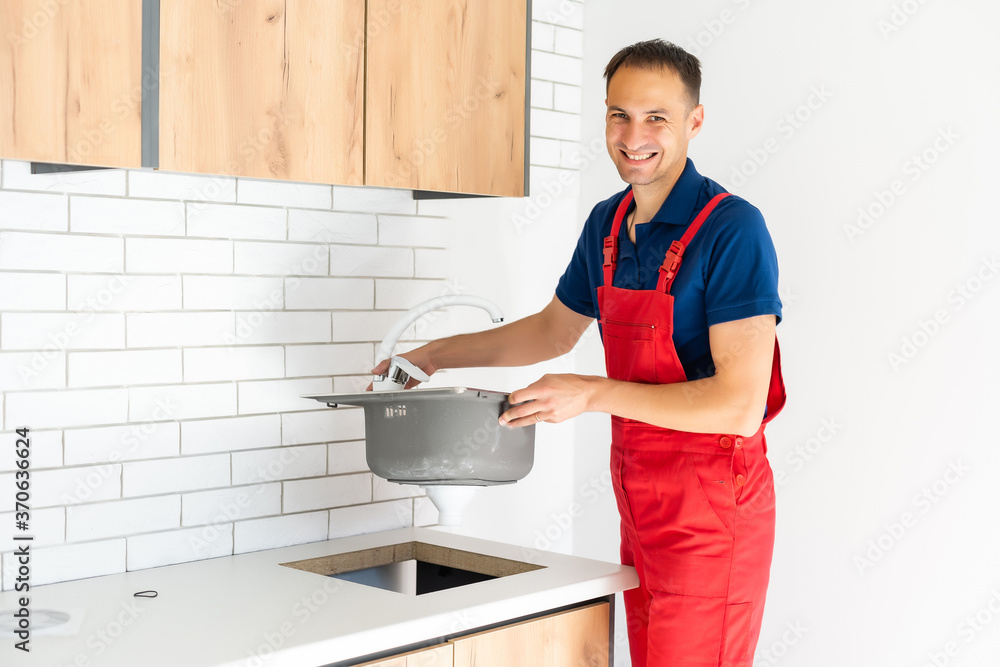Plumber putting a silicone sealant to installing a kitchen sink Plumber putting a silicone sealant to installing a kitchen sink