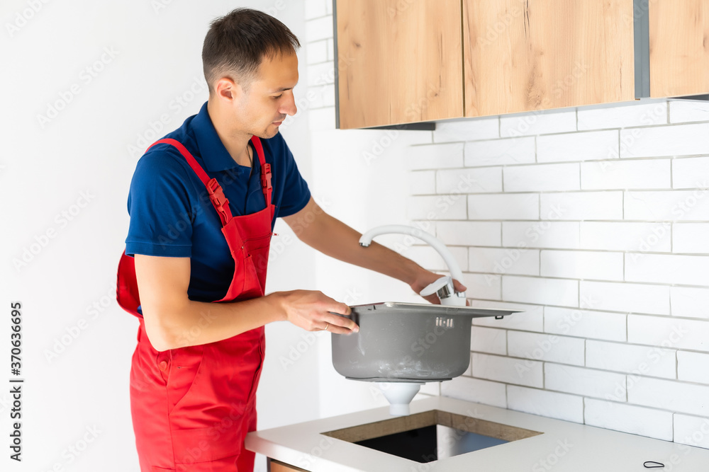 partial view of repairman in working overall fixing sink in kitchen partial view of repairman in working overall fixing sink in kitchen