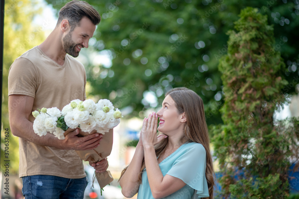 Bearded male presenting bouquet of flowers to surprised female Bearded male presenting bouquet of flowers to surprised female