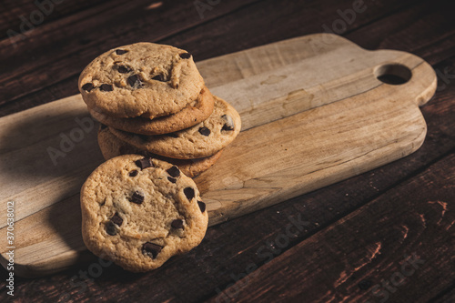 Pile of fresh baked chocolate chip cookies on a wooden board. 