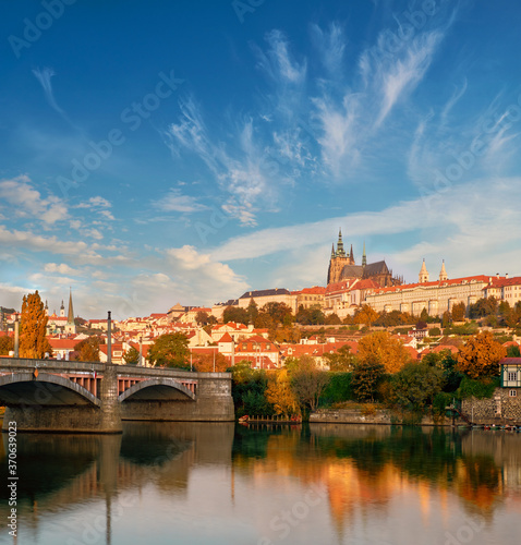 View on St. Vitus Cathedral and Prague Castle from across Vltava river on a bright Autumn day with reflection.