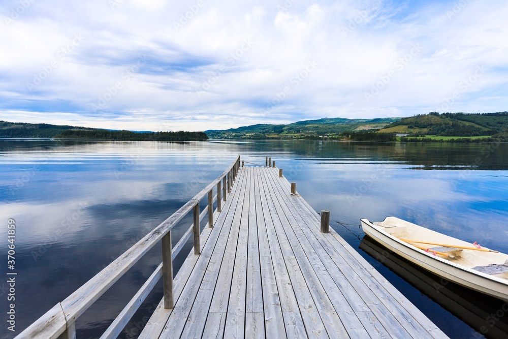Obraz premium Lake dock with boats on a summer afternoon in Norway. The water was calm before the storm.