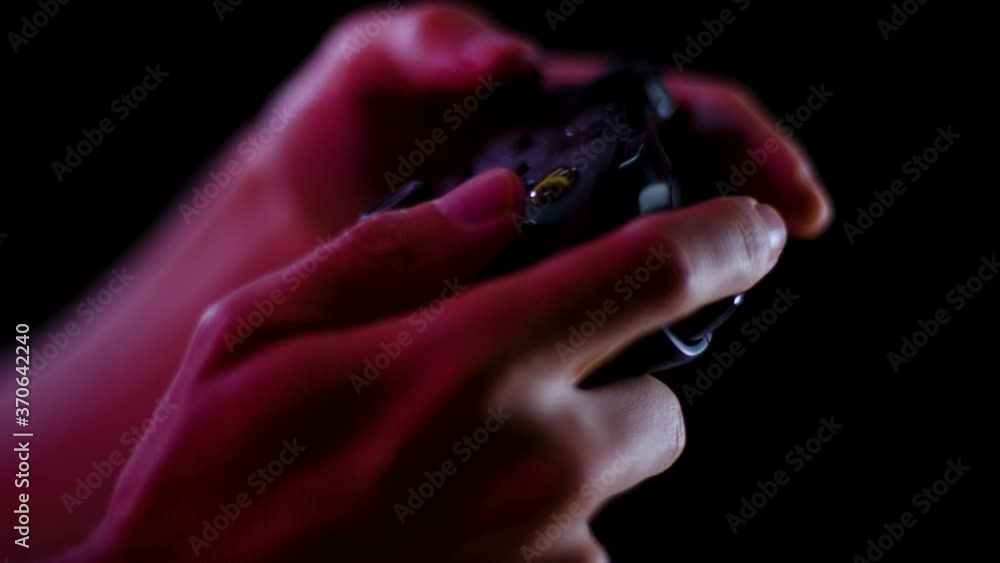 Playing video games in a darkened room with a black background close up on a controller buttons playing slowly Playing video games in a darkened room with a black background close up on a controller buttons playing slowly