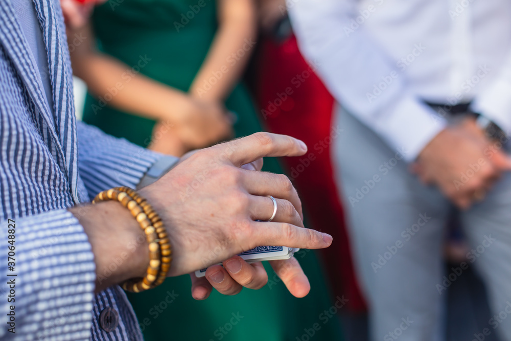 Fototapeta premium Magician showing card tricks focus in front of guests on party event wedding celebration, juggler performing show
