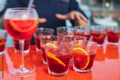 View of alcohol setting on catering banquet table  row line of red colored aperitif alcohol cocktails on a party  negroni and spritz  vodka  and others on decorated catering bouquet table event