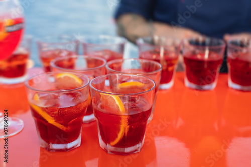 View of alcohol setting on catering banquet table, row line of red colored aperitif alcohol cocktails on a party, negroni and spritz, vodka, and others on decorated catering bouquet table event