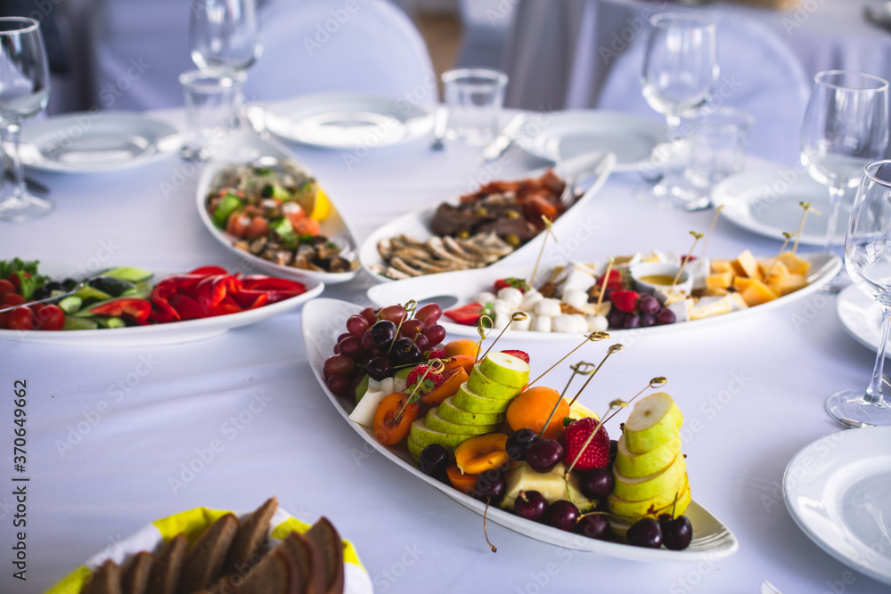 Beautifully decorated catering banquet table with different food snacks and appetizers on corporate christmas birthday party event or wedding celebration Beautifully decorated catering banquet table with different food snacks and appetizers on corporate christmas birthday party event or wedding celebration