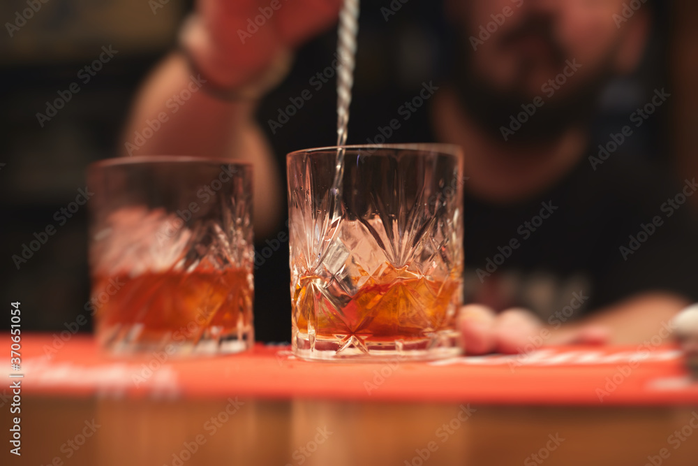 Row line of red colored negroni and spritz aperitif alcohol cocktails on a party of alcohol setting on catering banquet table, vodka, and others on decorated catering table event with bartender Row line of red colored negroni and spritz aperitif alcohol cocktails on a party of alcohol setting on catering banquet table, vodka, and others on decorated catering table event with bartender