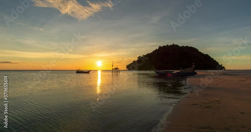Beautiful sunset view on the ocean with waves and reflection on the sand. A beached foreground log adds interest. Slow motion time lapse 4K footage. Shot at 2160p.