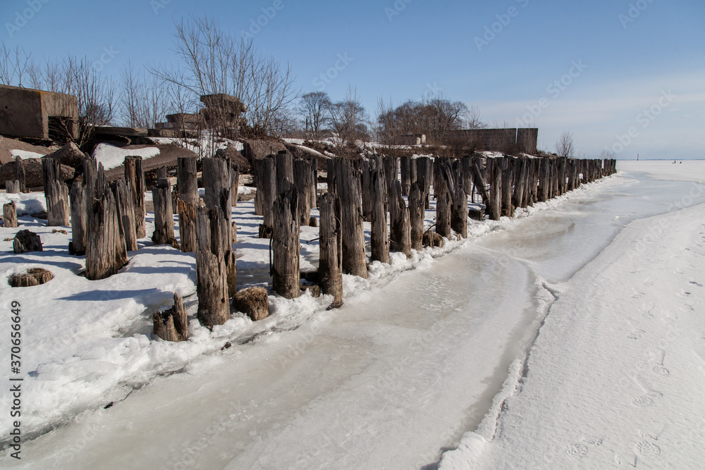 Rotten piles frozen in ice on the old pier Rotten piles frozen in ice on the old pier