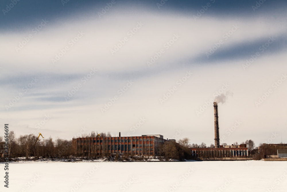 Winter industrial landscape of old soviet factory with brick tube