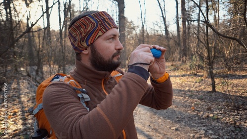 Tourist traveler tourist Caucasian man with a beard and a backpack looking through the shameful pipe on the nature landscape in the forest. A tourist looks at the wildlife in the telescope
