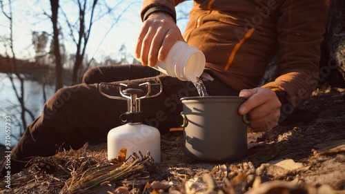 Foto Hands man Close-up pours water from flasks into a pot for boiling water on a gas