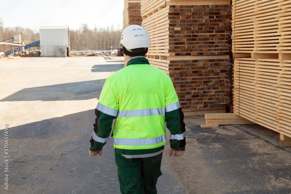 engineer next to a pile of boards at a sawmill engineer next to a pile of boards at a sawmill