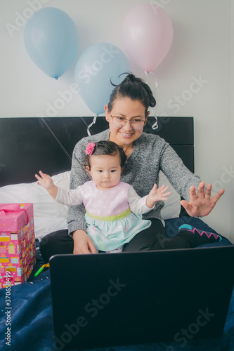 Madre y su bebé felices en tele llamada en la computadora celebrando el cumpleaños. Madre e hija festejando en teleconferencia durante la cuarentena por Covid.