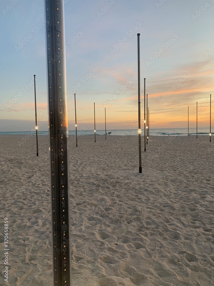 Decorative light posts on sandy beach during pastel sunset 