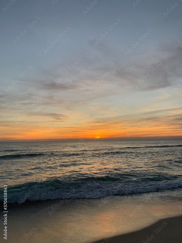 Vibrant sunset over calm sandy beach shoreline