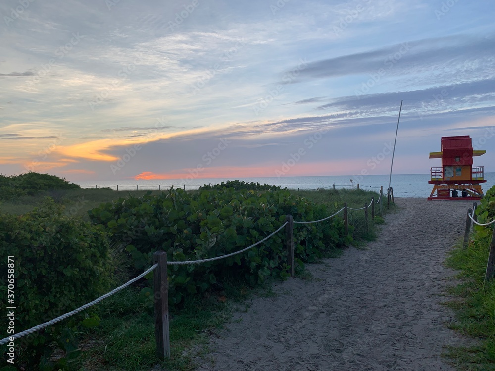 Pastel beach sunset near walkway and lifeguard tower