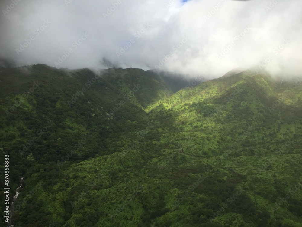 Sunny landscape view of green lush mountain terrain in the clouds
