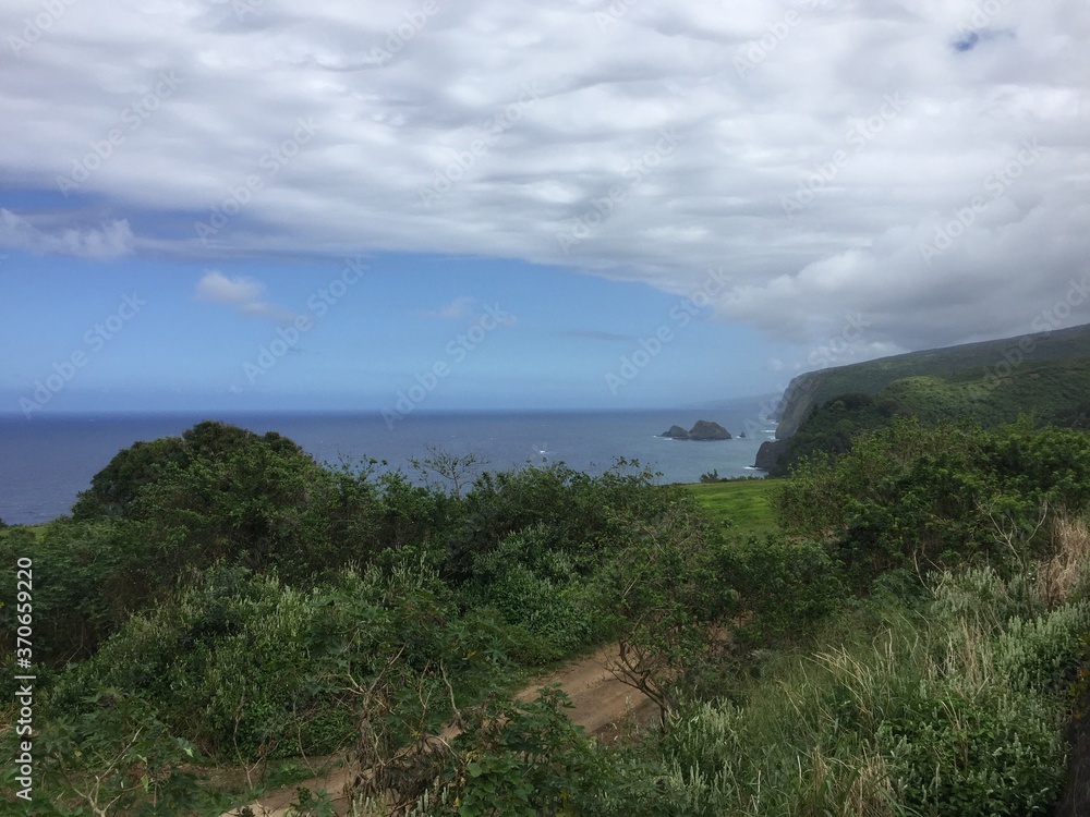 Cloudy blue skies over lush coastal mountain cliffs