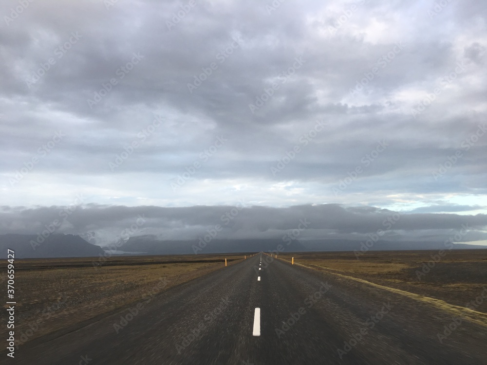 Empty road leading to rural cloudy mountains