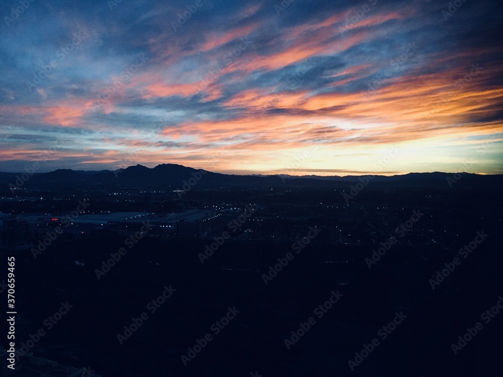 Landscape view of twinkling city lights under vibrant sunset