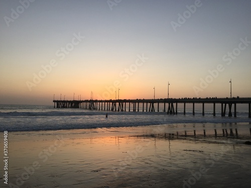 Landscape view of pier over sandy beach shore at sunset © Michael