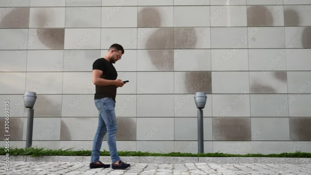 man with a mobile phone walks along the wall of a building on the street man with a mobile phone walks along the wall of a building on the street