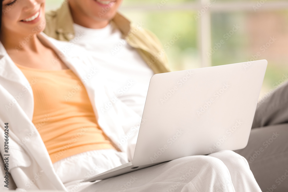 Young couple with laptop relaxing on sofa at home Young couple with laptop relaxing on sofa at home