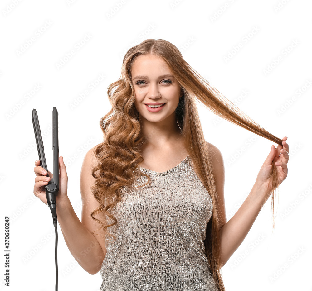 Beautiful young woman with flattening iron for hair against white background Beautiful young woman with flattening iron for hair against white background