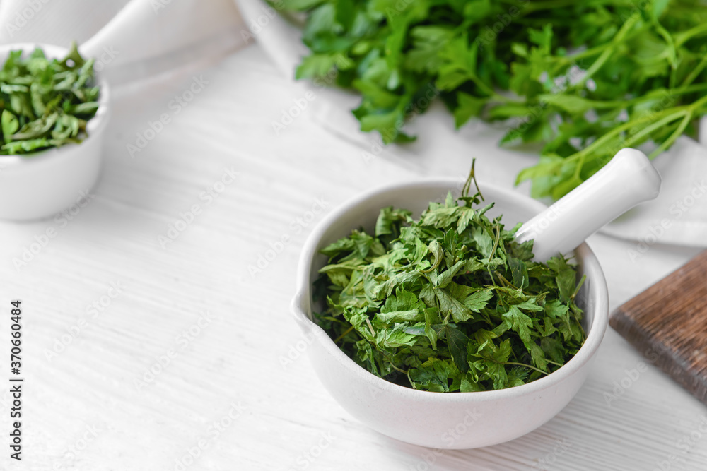 Mortar with dry parsley on table