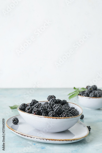 Bowl with tasty blackberry on table