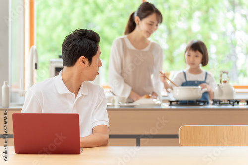 キッチンで働くお父さんと見守る親子 © taka