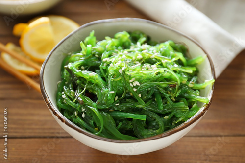 Bowl with tasty seaweed salad on table