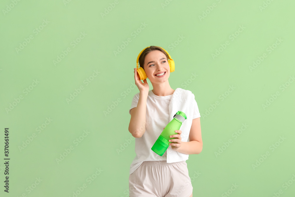 Sporty young woman with headphones and water on color background Sporty young woman with headphones and water on color background